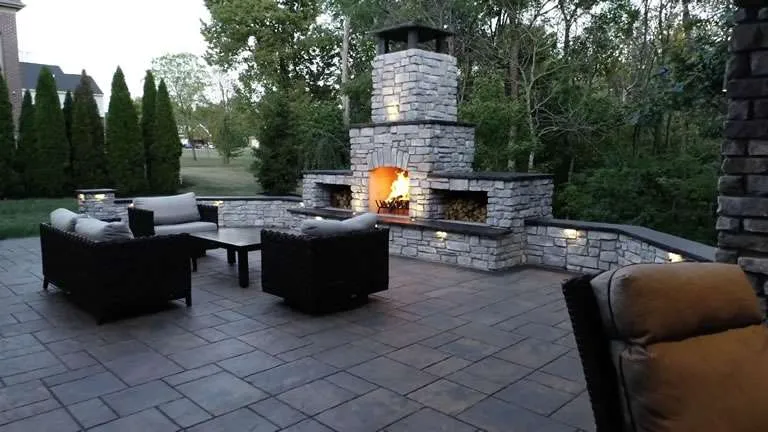 Two-story brick house with warm landscape lighting highlighting the front yard at dusk.